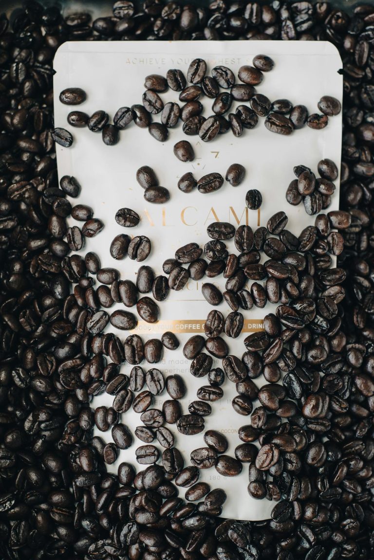 Rich brown coffee beans scattered over a packaging surface, showcasing aroma and freshness.